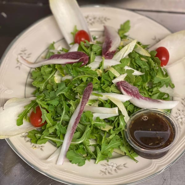 A fresh Rini's Italian salad with arugula, endive, radicchio, cherry tomatoes, and balsamic dressing.