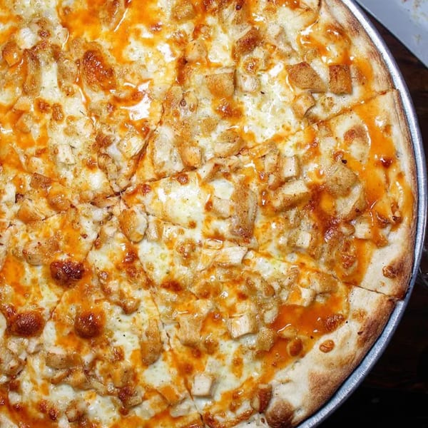 Close-up of a Rini's Restaurant & Wine Bar buffalo chicken pizza, with melted cheese and orange sauce.